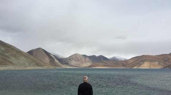 Homepage canva   man traveler standing alone on cliff lake and foggy mountains on